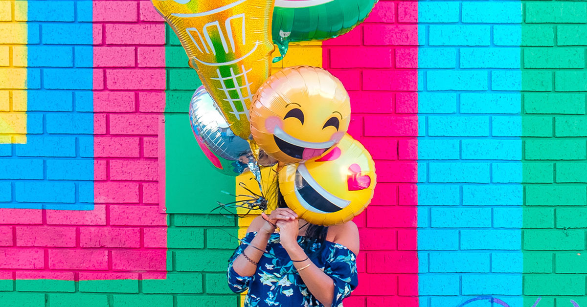 how often should i floss my teeth a day? a girl holding up big smiley face balloons!